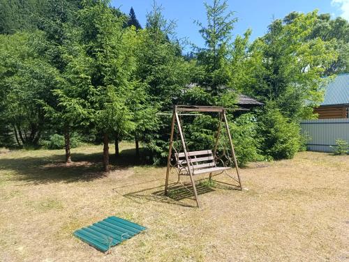 a wooden bench sitting in a yard next to trees at Біля Синевіру in Synevyrsʼka Polyana
