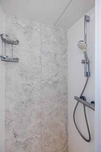 a bathroom with a shower with a stone wall at Floating holiday home close to AMS in Loenersloot