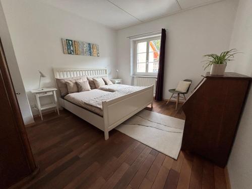 a white bedroom with a bed and a window at Hôtel-Restaurant de la Demi-Lune in Saint-Ursanne
