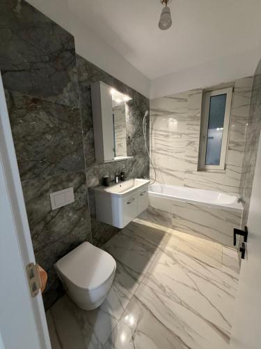a bathroom with a toilet and a sink and a tub at Apartament Giovanni in Giroc