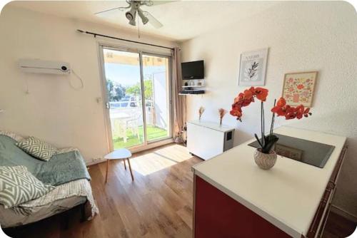 a living room with a table with a vase of flowers at Appartement cosy Le Phoebus in Canet-en-Roussillon