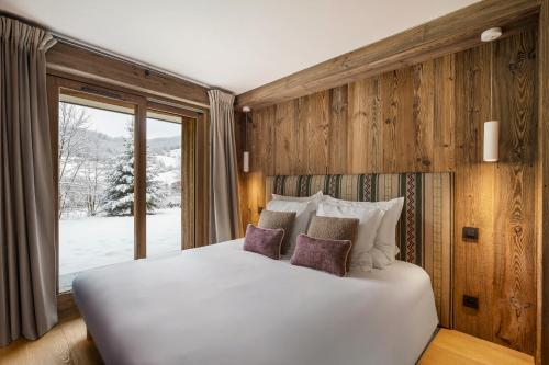Un dormitorio con una cama blanca y una ventana. en Luxury Chalet Black Mountain - 4BR, Sleeps 10, Fireplace, Mountain Views & Garden - Megève, en Megève