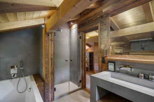 Un baño con bañera, lavabo y ducha. en Luxury Chalet Black Mountain - 4BR, Sleeps 10, Fireplace, Mountain Views & Garden - Megève, en Megève