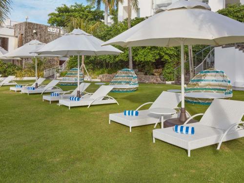une rangée de chaises longues et de parasols sur l'herbe dans l'établissement Mövenpick Hotel Mactan Island Cebu, à Mactan