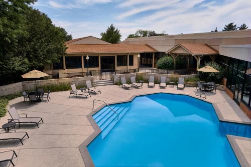 a swimming pool with patio furniture and a building at Fort Collins Marriott in Fort Collins