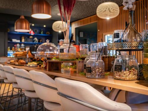 een restaurant met een lange toonbank met stoelen en potten vol eten bij Mercure Saint Omer Centre Gare in Saint-Omer