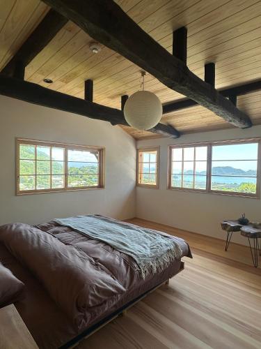 a bedroom with a large bed in a room with windows at Yugashira Kuu ゆがしら空 in Imabari