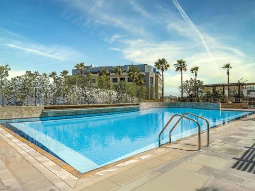 a large swimming pool with palm trees and a building at Swissôtel Al Ghurair Dubai in Dubai