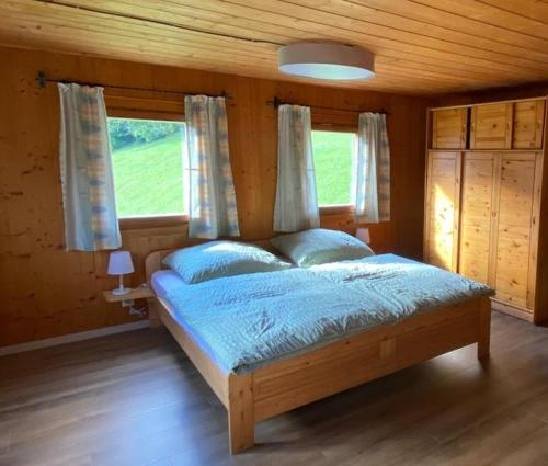 a bedroom with a bed with blue sheets and windows at Haus Renard in Bartholomäberg