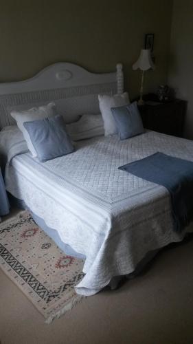 a large white bed with blue pillows in a bedroom at Avoca River Cabins in Addo