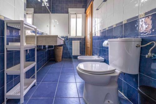 ein blau gefliestes Badezimmer mit Toilette und Waschbecken in der Unterkunft Bonita casa en Torrejón del Rey in Torrejón del Rey