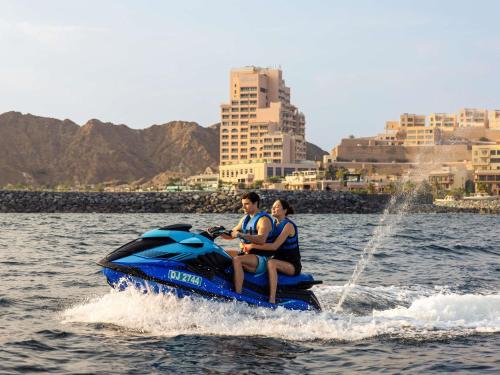 a man and woman riding on a jet ski in the water at Fairmont Fujairah Beach Resort in Al Aqah