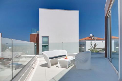 a balcony with two white chairs and a table at Seaview Luxury Villa Jacuzzi & Pool! 2 Min Beach in Protaras