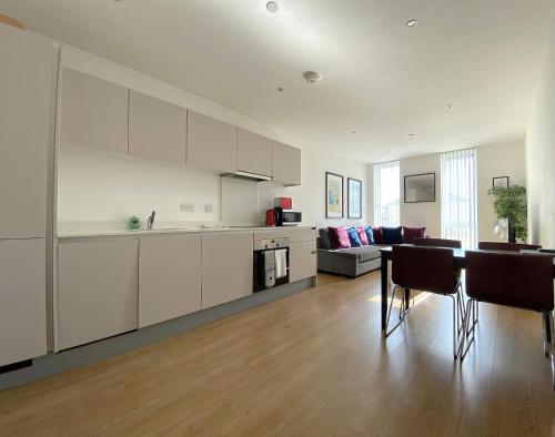 a kitchen and living room with white cabinets and a table at Bracknell RWH Spectacular Two Bedroom Apartment in Bracknell
