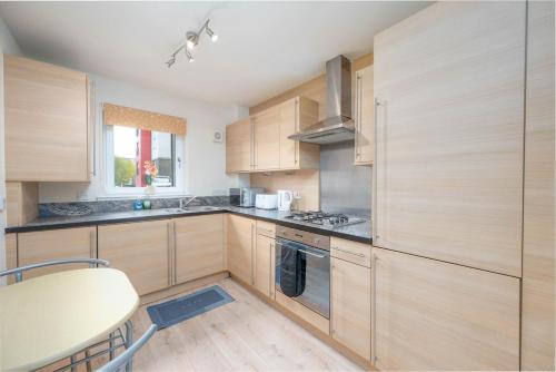 a kitchen with wooden cabinets and a table in it at Aberdeen 2BR Flat Near Airport & City Centre in Aberdeen