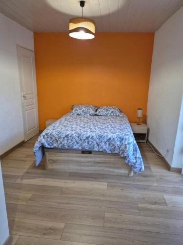 a bedroom with a bed and a orange wall at Le logis du Colombier in Culoz