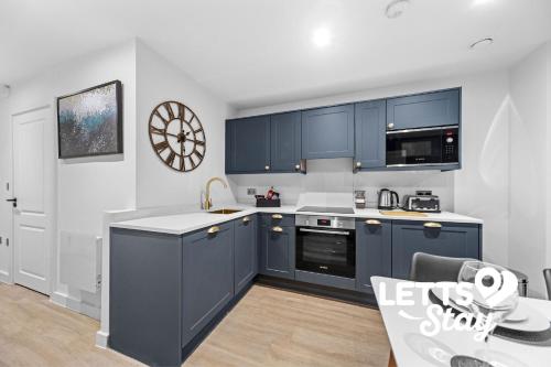 een keuken met blauwe kasten en een tafel. bij The Old Schoolhouse in Leeds