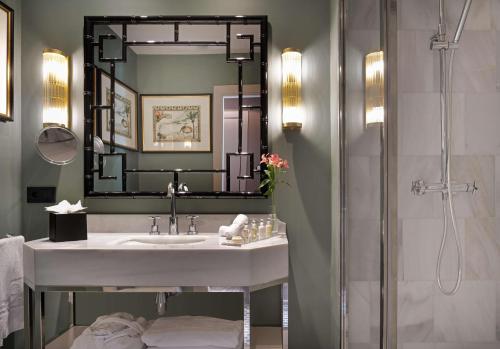 une salle de bain avec un lavabo et un miroir dans l'établissement NH Collection Colón Valencia, à Valence