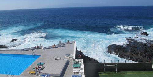 a swimming pool next to a body of water at Feel the Breath of the Ocean in Puerto de Santiago