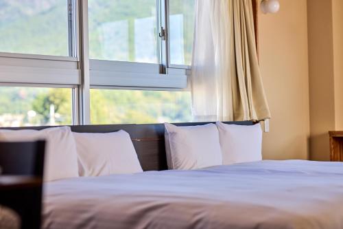 a bed with white pillows in front of a window at ホステル サクヤ in Fujiyoshida