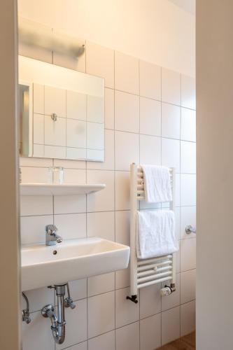 a bathroom with a sink and a mirror and towels at Hotel Kaisergarten Neuenrade in Neuenrade