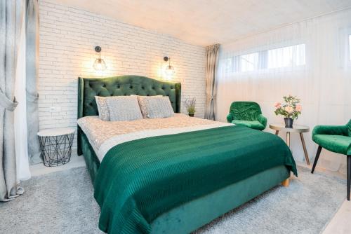 - une chambre avec un lit vert et 2 chaises vertes dans l'établissement Žalia kopa near the beach apartments, à Palanga
