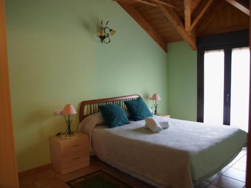 a bedroom with a large bed with blue pillows at Casa Miguel Périz in Sorripas