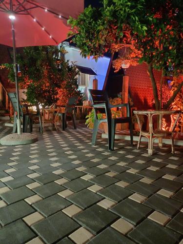 a patio with chairs and tables and an umbrella at Guest House Adilaj in Berat
