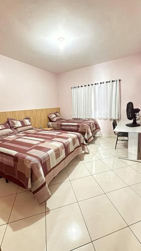 two beds in a room with a tiled floor at Casa Rosa de Saron in Triunfo