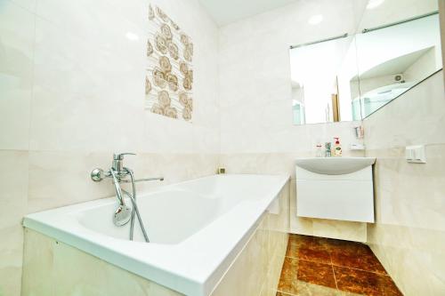 a white bathroom with a tub and a sink at Квартира посуточно двокімнатна у мікрорайоні Садовий Мережа Alex Apartments Документи для відряджень ФОП 3 група in Poltava