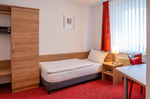 a small room with a bed and a table at Hotel Kaisergarten Neuenrade in Neuenrade