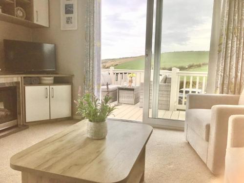 a living room with a table and a large window at NV45 Beautiful durdle door holiday park in West Lulworth