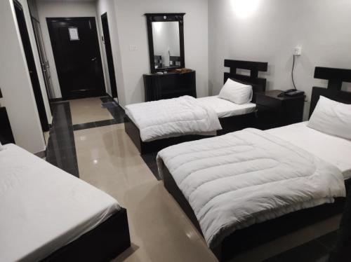 a room with three beds and a mirror at Moon Living Apartment Peshawar in Peshawar