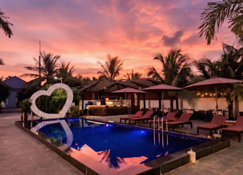 a resort pool with a heart sign in front of a sunset at The Step Hotel kampot in Kampot