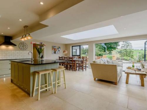 a kitchen and living room with a couch and a table at Hen Llwyn By Birch Stays New Home in Llangadwaladr