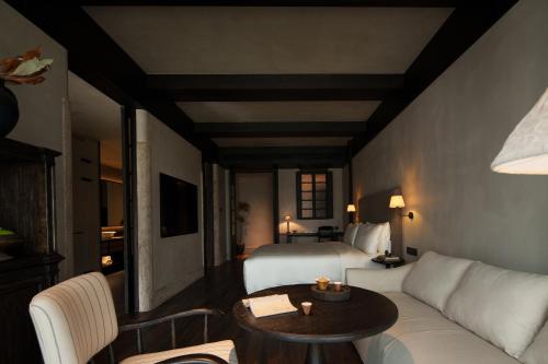 ein Hotelzimmer mit einem Bett, einer Couch und einem Tisch in der Unterkunft Chengdu 6500 Hotel Kuanzhai Alley Citang Street Branch in Chengdu