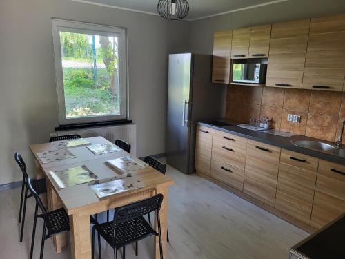 een keuken met een houten tafel en een koelkast bij Hotelik nad jeziorem w Łasinie in Łasin