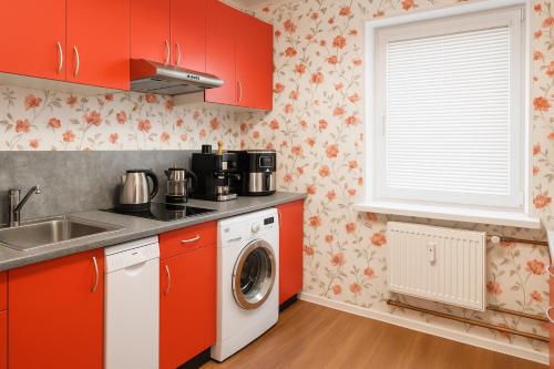 eine Küche mit roten Schränken und einer Waschmaschine in der Unterkunft Friendly two-room apartment in Sigulda