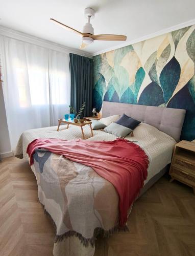 a bedroom with a large bed with a painting on the wall at Light Blue Apartment Orihuela Costa in Orihuela Costa
