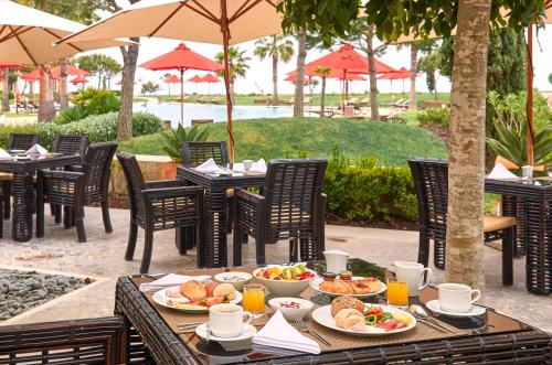 ein Tisch mit Essen darauf mit Stühlen und Sonnenschirmen in der Unterkunft Cascade Wellness Resort in Lagos