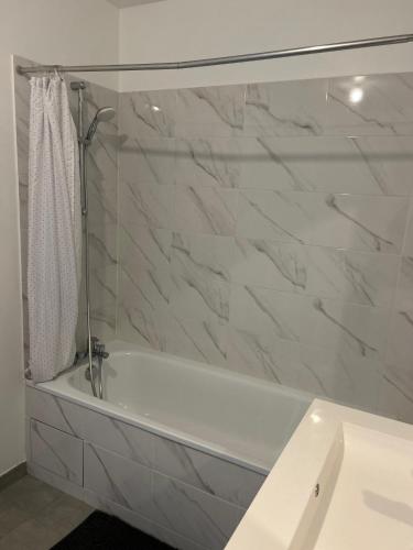 a white bath tub in a bathroom with marble walls at Appartement cosy proche Disneyland in Serris