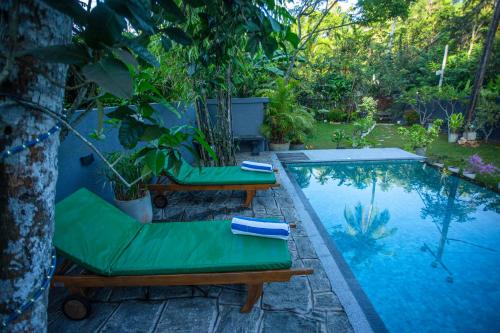 une piscine avec deux chaises longues à côté dans l'établissement Saku Residence, à Unawatuna