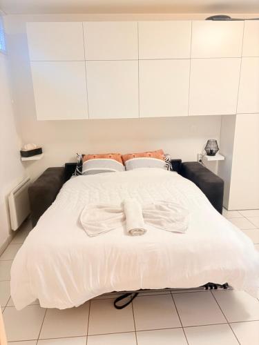 ein Schlafzimmer mit einem weißen Bett mit einer Schleife darauf in der Unterkunft studio proche Orly et villes 91 in La Ville-du-Bois