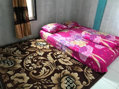 a bed with a pink blanket on top of a carpet at Komodo Wisata Homestay in Komodo