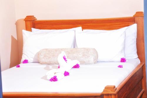 un lit blanc avec un animal rembourré dans l'établissement Mambo Villa, à Matemwe
