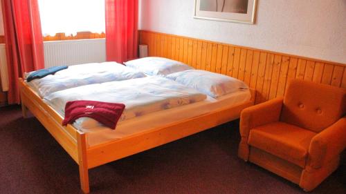 a bed in a room with a chair next to a window at Chata Rosa in Malenovice
