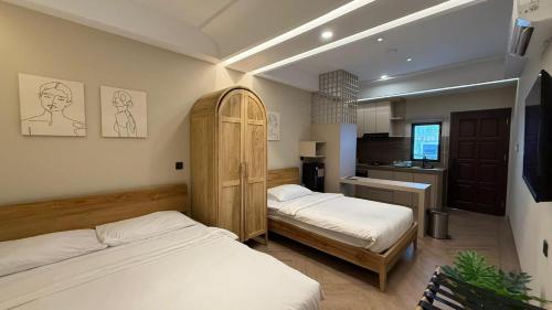 a bedroom with two beds and a kitchen in it at Palm Stay Residence in Nagoya