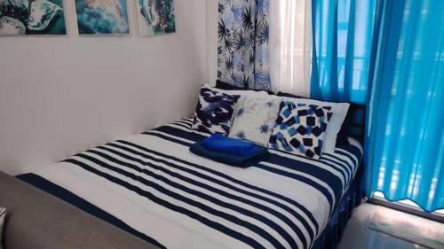 a bed with blue and white sheets and pillows at E & R Staycation Condotel near Mall of Asia in Manila