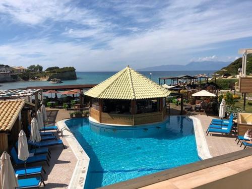a swimming pool with a gazebo and chairs and the ocean at Exclusive Del Mare Hotel in Sidari