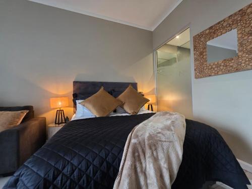 a bedroom with a bed with a black comforter and pillows at The Capital Trilogy Hotel in Pretoria